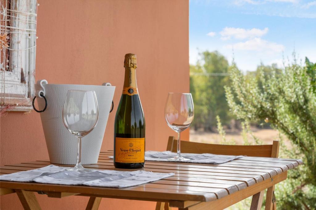 a bottle of wine sitting on a table with two glasses at Le tenute del mandarino in Elmas