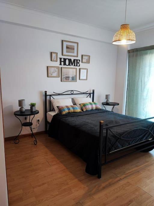 a bedroom with a black bed and two tables at Apartamento acolhedor Oeiras in Barcarena