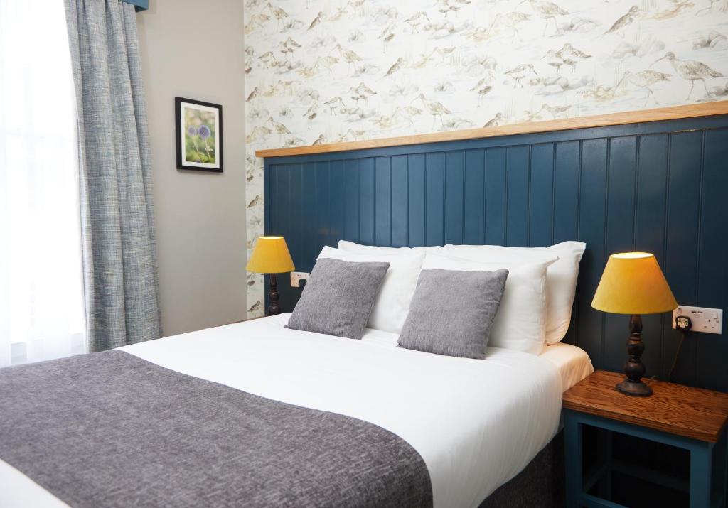 een slaapkamer met een groot bed met een blauwe muur bij The Bell Hotel Woburn By Greene King Inns in Woburn