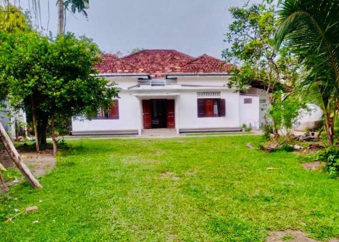 a white house with red windows and a yard at Shine Breeze villa in Weligama