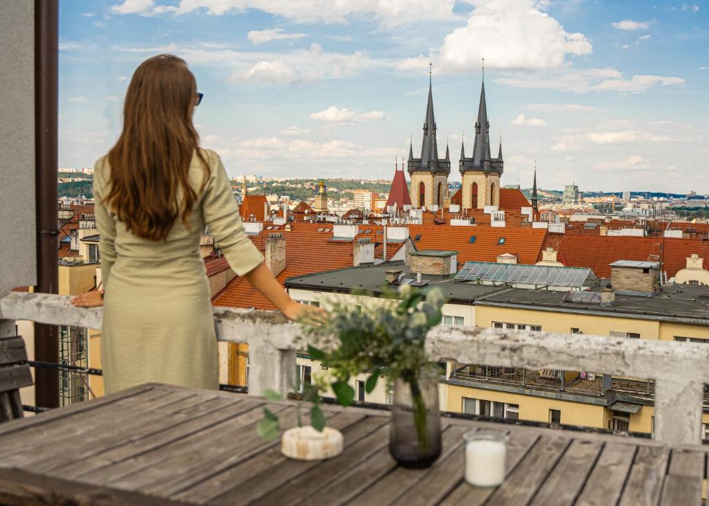 Eine Frau steht auf einem Balkon mit Blick auf eine Stadt in der Unterkunft Sunny Condo in Holešovice by Prague Days in Prag
