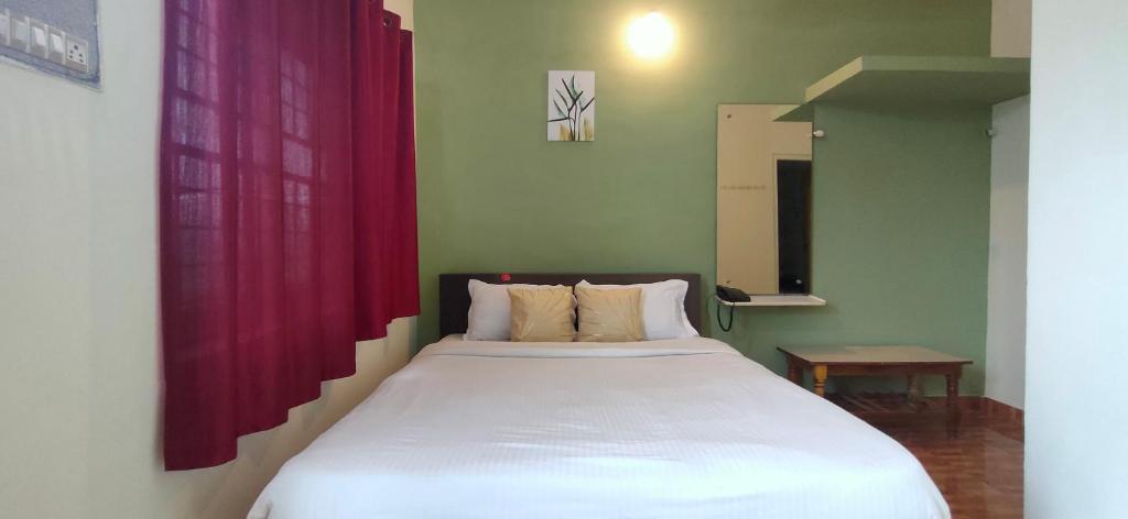 a bedroom with a large white bed with a red curtain at Lucky Inn Coorg in Kushālnagar