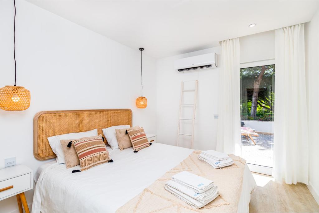 a white bedroom with a bed and a window at Soltroia lake Dream house in Troia