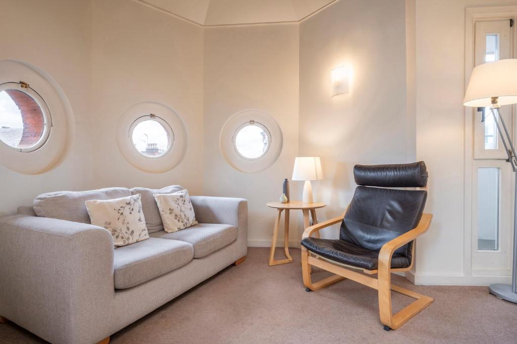 ein Wohnzimmer mit einem Sofa und einem Stuhl in der Unterkunft The Aristocrat - Fitzrovia - by Frankie Says in London
