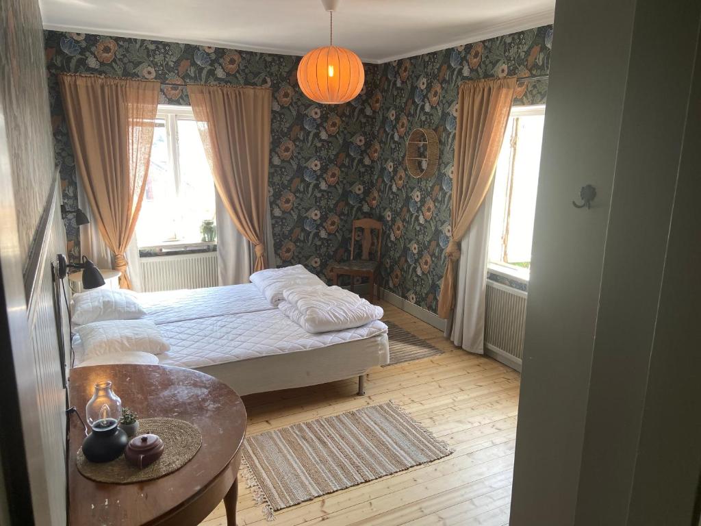 a bedroom with a bed and a table and windows at Elisabets Vandrarhem Hemse in Hemse