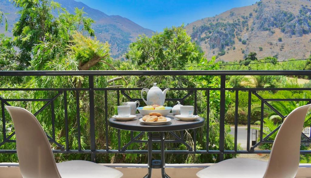 a table with a tea set on a balcony with mountains at Artemida Pansion in Kournás