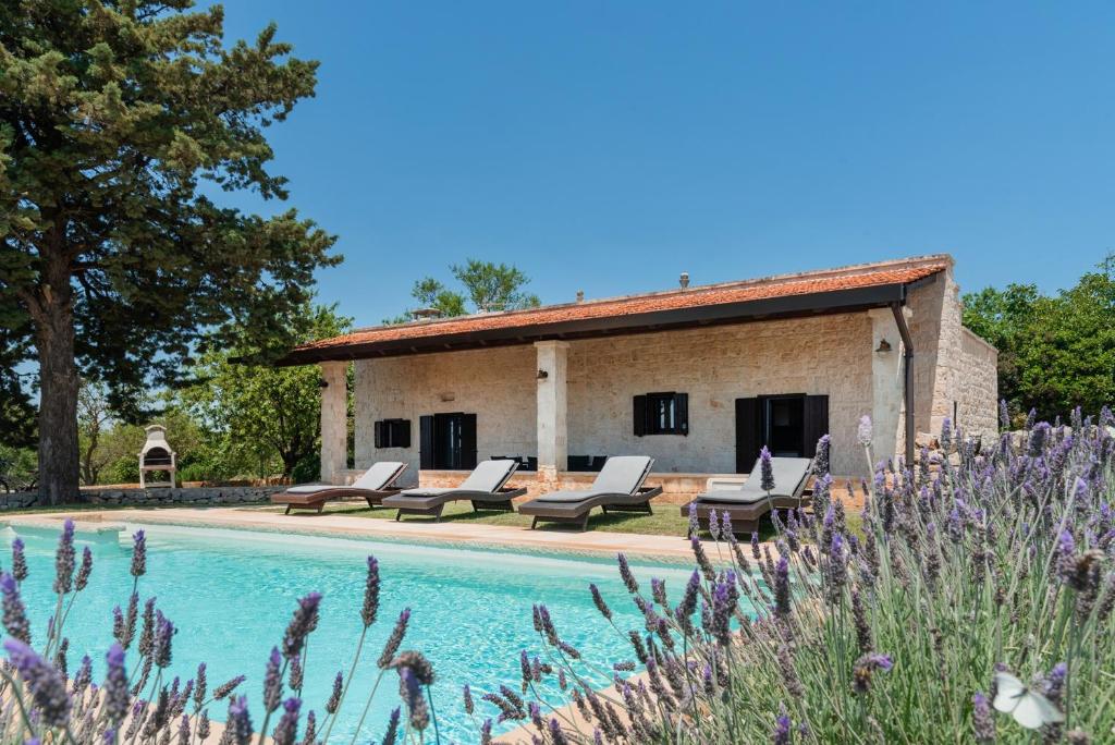 une maison avec piscine devant un immeuble dans l'établissement Trullo Badessa, à Martina Franca