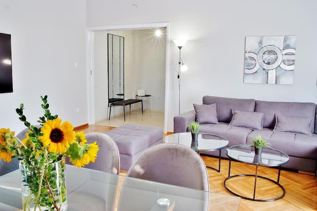 Melia Residence Acropolis - NEW في أثينا: غرفة معيشة مع أريكة وطاولة وكراسي