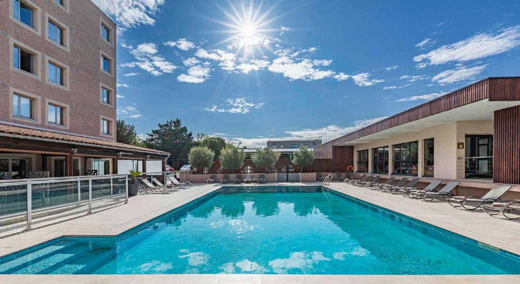 a swimming pool in front of a building at Best Western Marseille Aeroport in Vitrolles