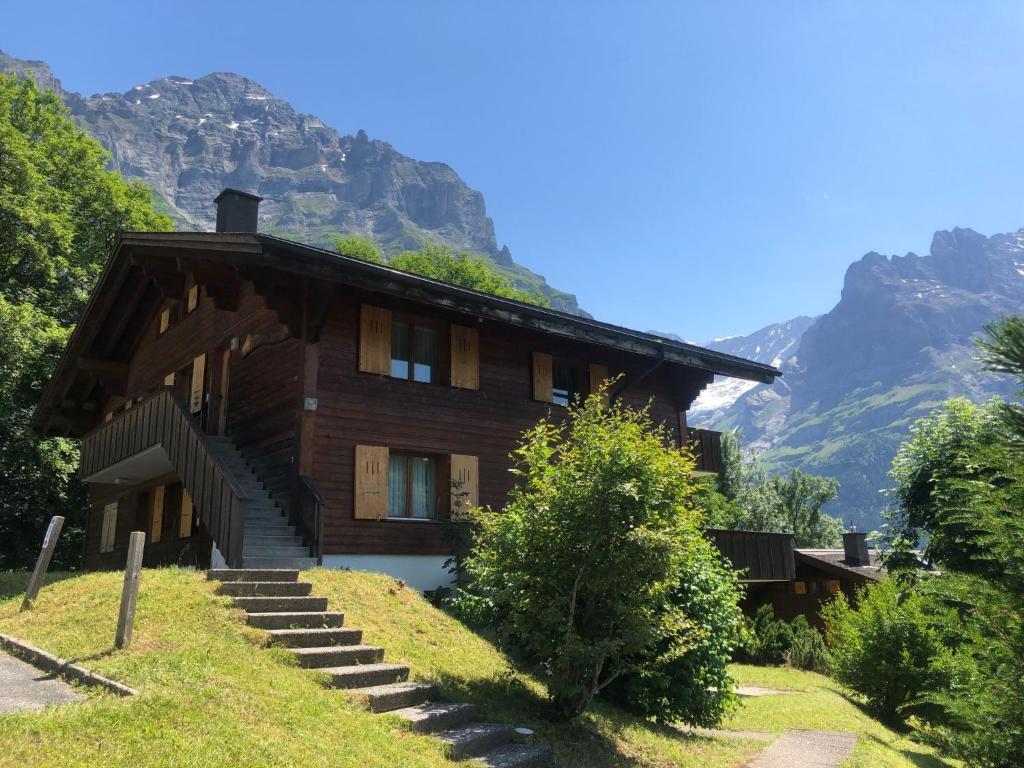 a house on a hill with mountains in the background at Apartment Chalet Sunneblick by Interhome in Grindelwald