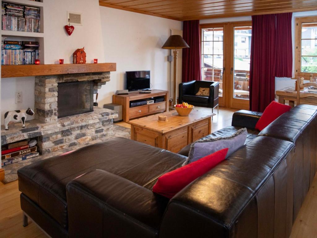 a living room with a leather couch and a fireplace at Apartment Daphné A 32 by Interhome in Villars-sur-Ollon