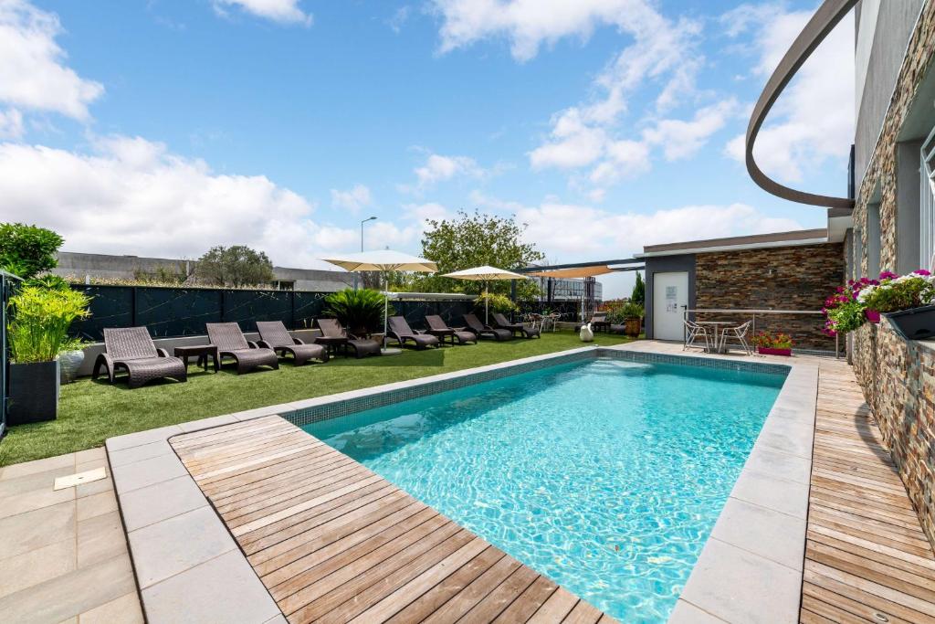 a swimming pool in a backyard with a wooden deck at Sure Hotel by Best Western Beziers Le Monestie in B&eacute;ziers