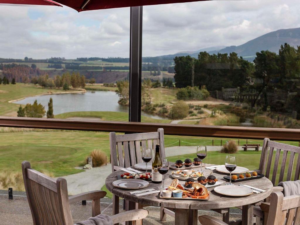 una mesa con copas de vino y comida y una gran ventana en Fable Terrace Downs Resort by MGallery en Windwhistle