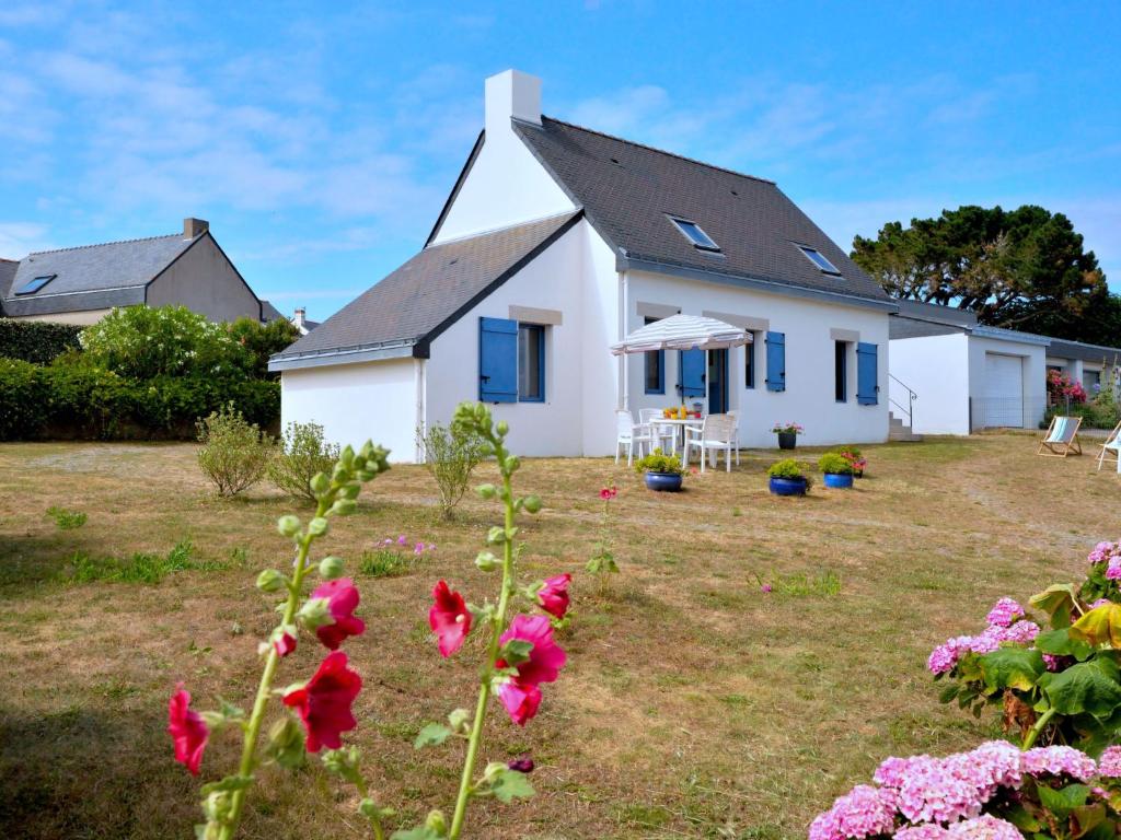 a white house with blue windows and flowers at Holiday Home La Lousse by Interhome in Assérac