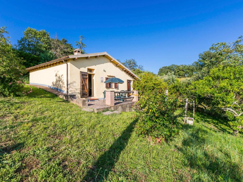 une petite maison blanche sur une colline herbeuse dans l'établissement Holiday Home Grilli by Interhome, à Scansano