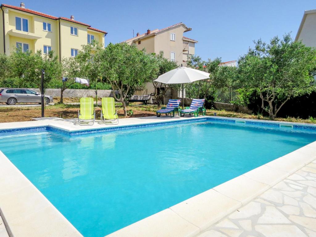 una piscina con sillas y sombrilla en Apartment Katarina 5 by Interhome, en Brodarica