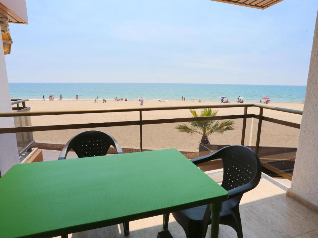 a green table and chairs on a balcony overlooking the beach at Apartment MemLing-1 by Interhome in Vilafortuny