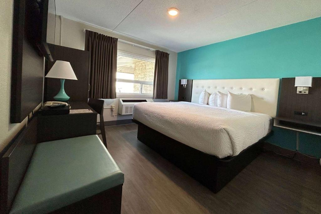 Howard Johnson by Wyndham Thunder Bay في ثاندر باي: غرفة نوم بسرير كبير وجدار ازرق