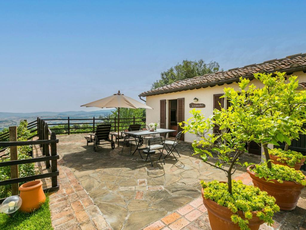 a patio with a table and chairs and an umbrella at Holiday Home Ciliegiolo by Interhome in Cinigiano