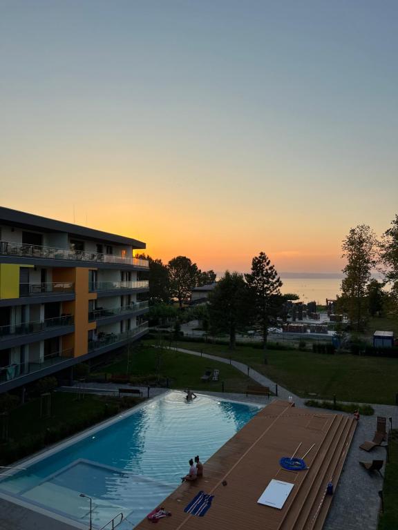 einem Pool vor einem Gebäude bei Sonnenuntergang in der Unterkunft Chill Panorama Apartman in Siófok