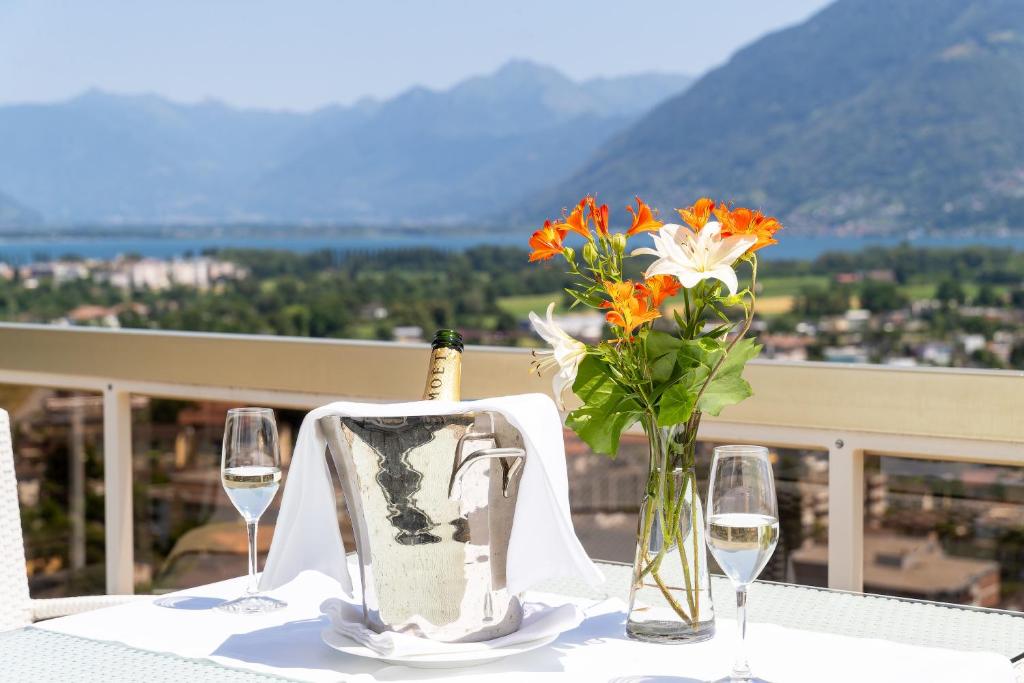 uma mesa com copos e uma garrafa de vinho e flores em Hotel Ascona em Ascona