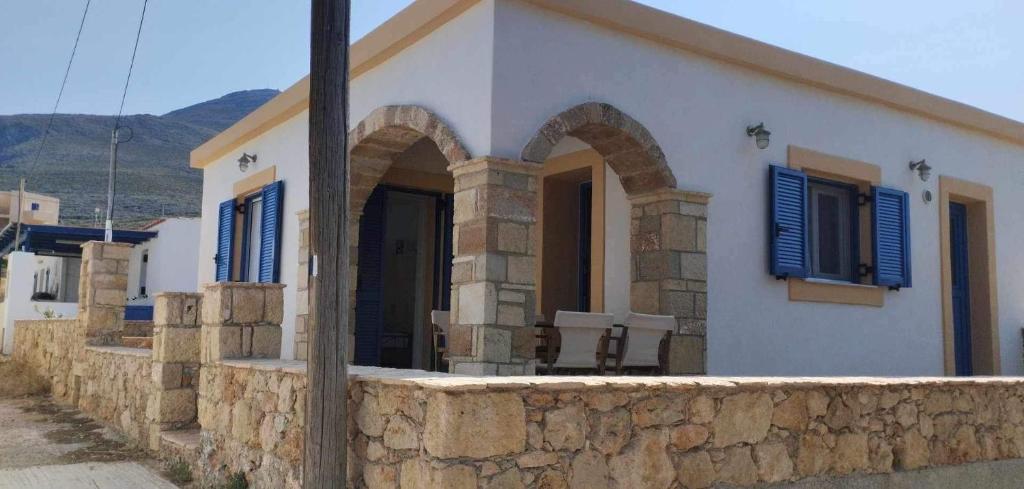 a house with blue shutters and a stone wall at Diakofti house by the sea - Kythoikies hoilday houses in Kythira