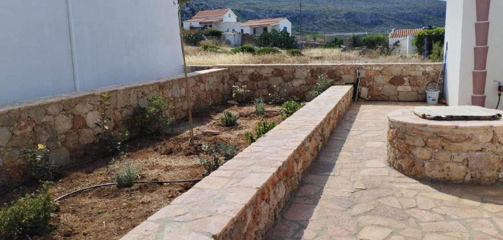 a stone retaining wall with a bench in a garden at Diakofti house by the sea - Kythoikies hoilday houses in Kythira