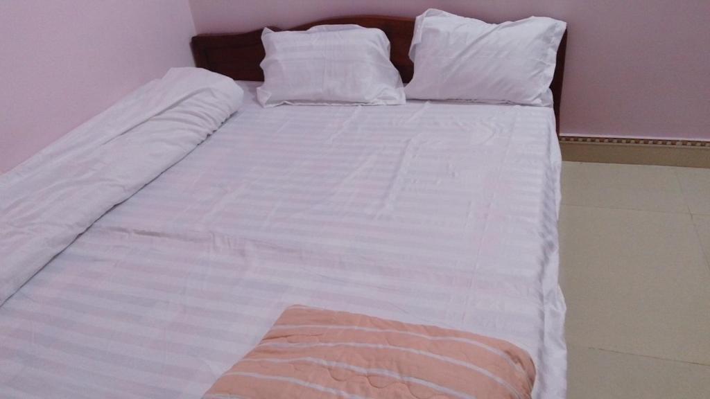 uma grande cama branca com lençóis e almofadas brancos em New Homestay em Ha Giang