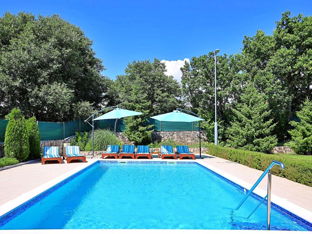 a swimming pool with blue chairs and umbrellas at Holiday Home Bili dvori by Interhome in Čaporice