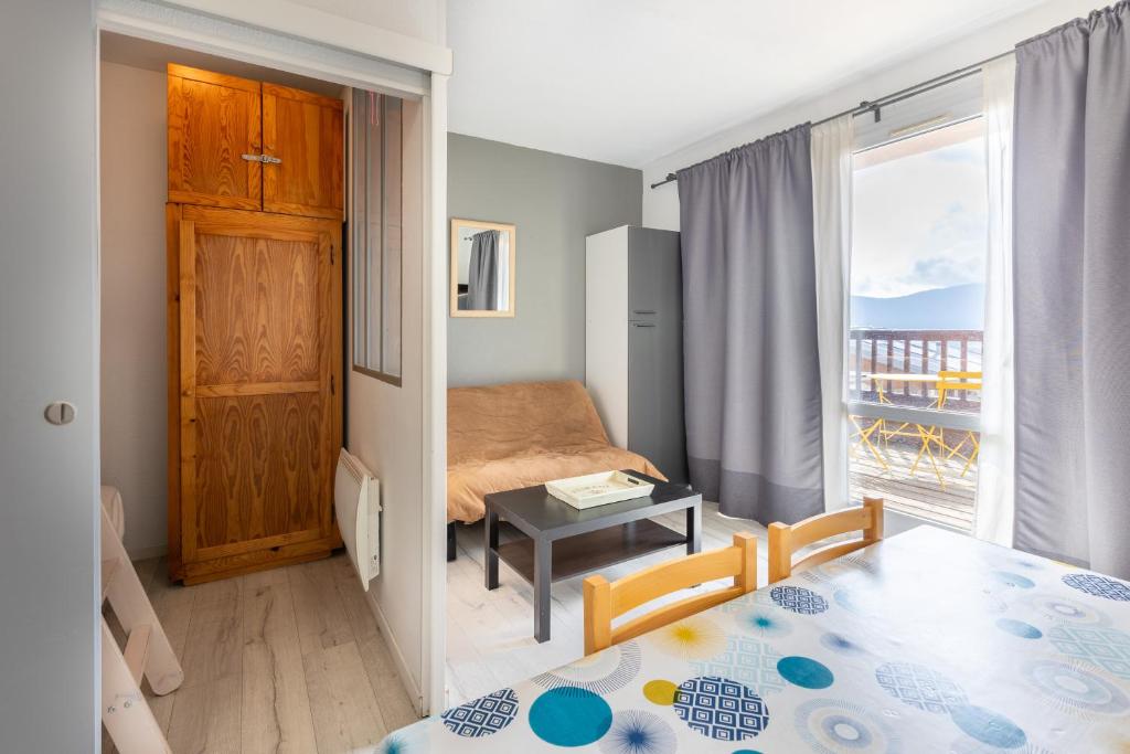 Cette petite chambre comprend un lit, une table et une fenêtre. dans l'établissement Zénitude - Appartement au pied des pistes, aux Angles