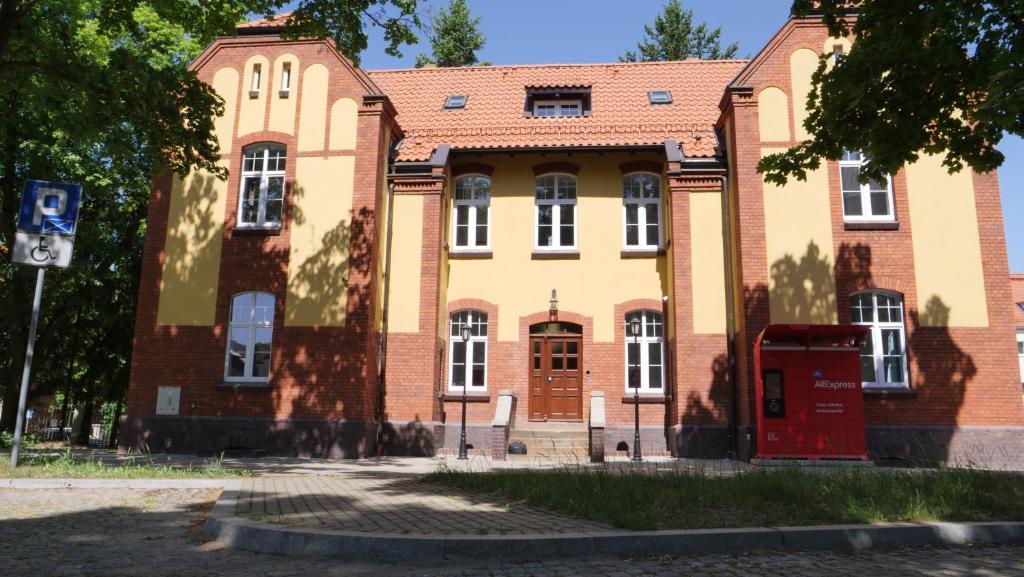 un vieux bâtiment en briques avec une cabine de téléphone rouge devant lui dans l'établissement Szewczenki 3, à Olsztyn