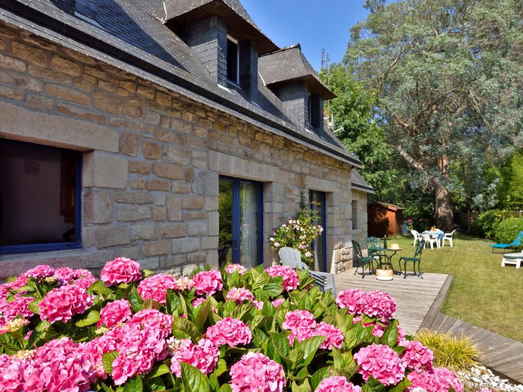 un jardin avec des fleurs roses devant une maison en pierre dans l'établissement Holiday Home St Adrien by Interhome, à Ploemeur