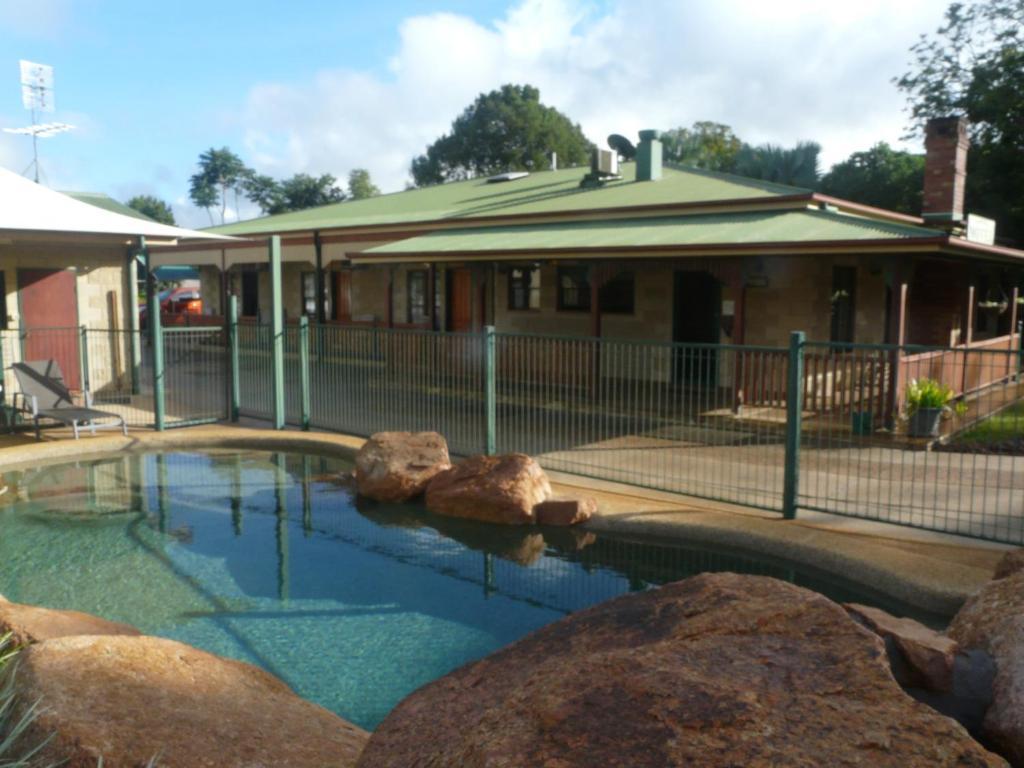 a swimming pool with rocks in front of a house at Curtain Fig Motel in Yungaburra