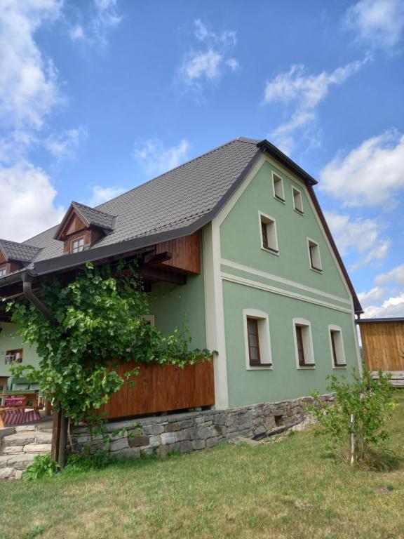 una casa verde con techo negro en Chalupa U Kravína en Rtyně v Podkrkonoší