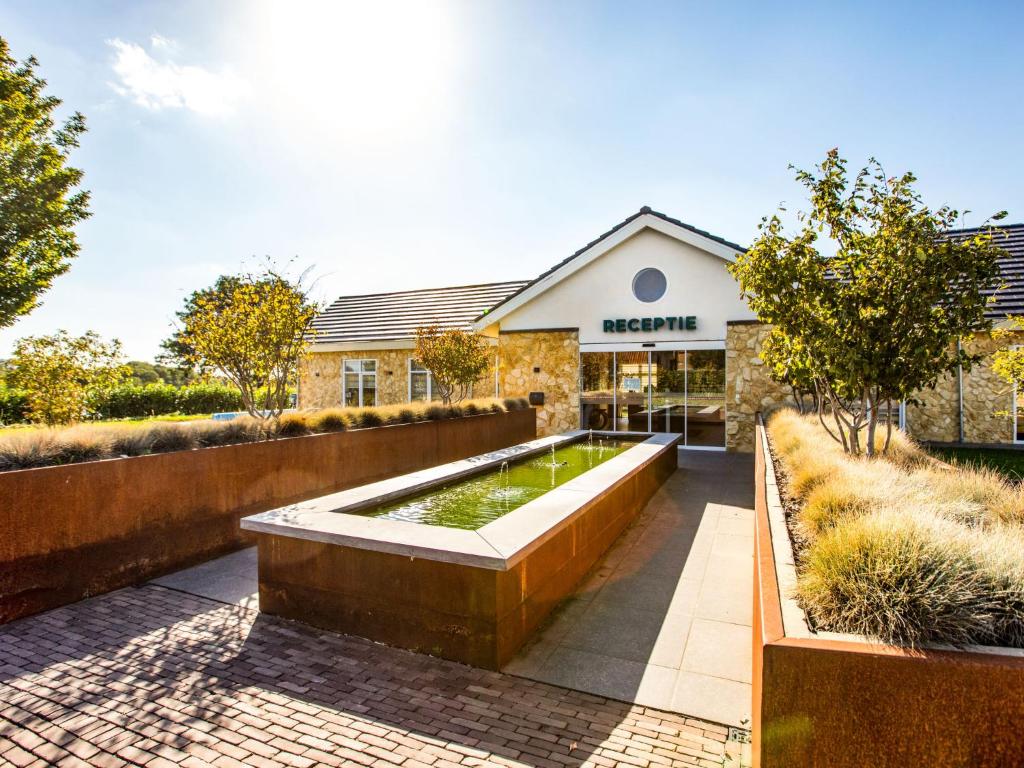 贝梅伦Holiday Home Green Resort Mooi Bemelen-1 by Interhome的一座花园,在一座建筑前设有一个大型游泳池