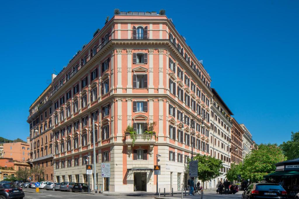 un grand bâtiment rose dans une rue de la ville dans l'établissement UNAHOTELS Trastevere Roma, à Rome