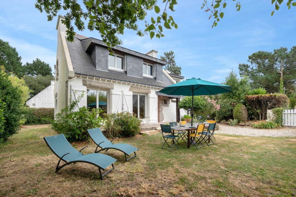 a table and chairs with an umbrella in front of a house at Detente au calme et pres de la plage in Saint-Gildas-de-Rhuys