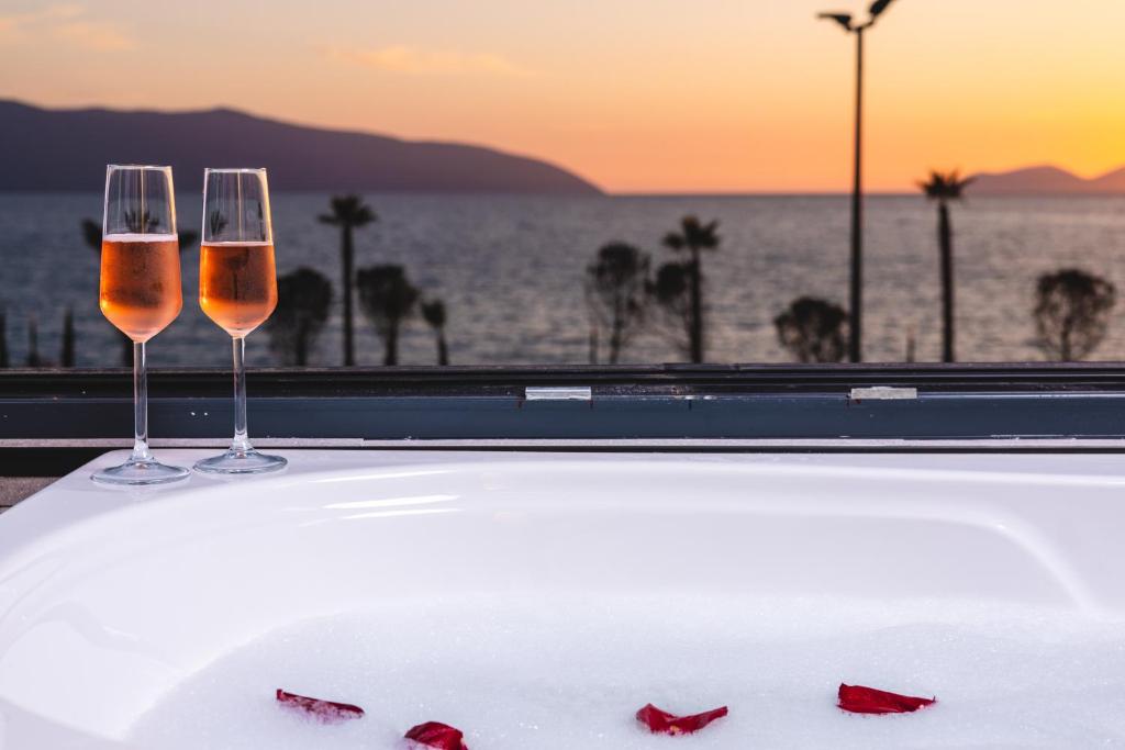 two wine glasses on a table with a view of the ocean at Azar Luxury Suites in Vlorë