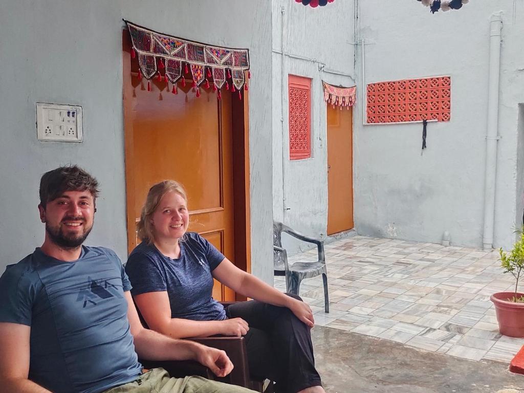 a man and a woman sitting in front of a house at Little prince guest house & homestay in Bikaner