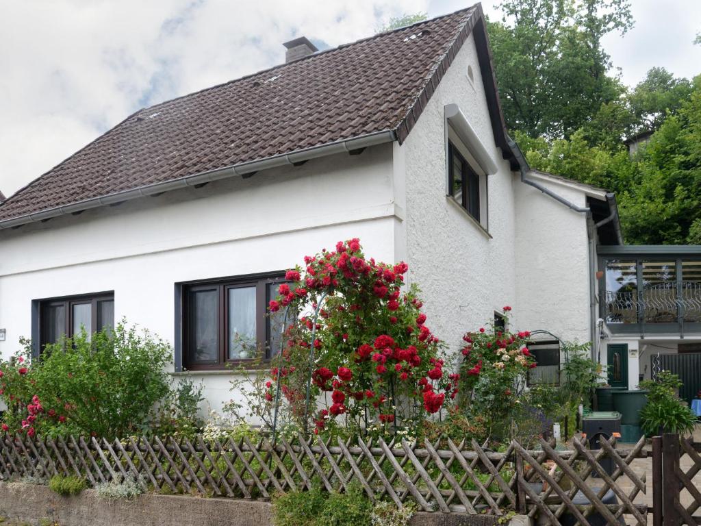 a white house with red flowers and a fence at Apartment Am Dohlenberg by Interhome in Schieder-Schwalenberg