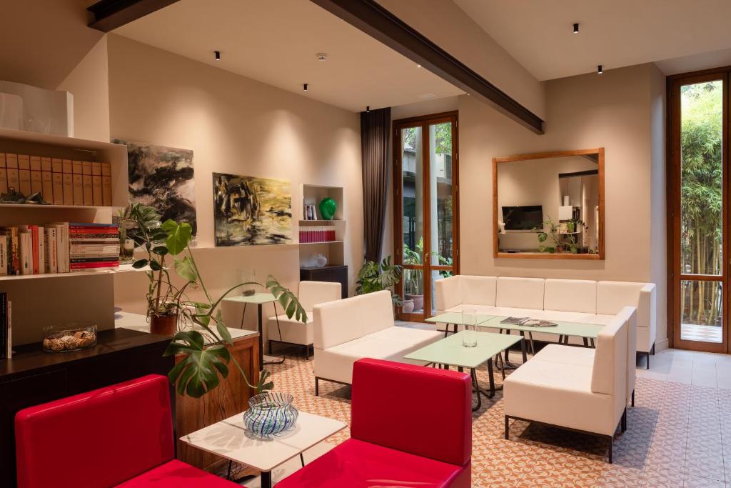 a living room with white furniture and red chairs at Hotel Caravaggio in Florence