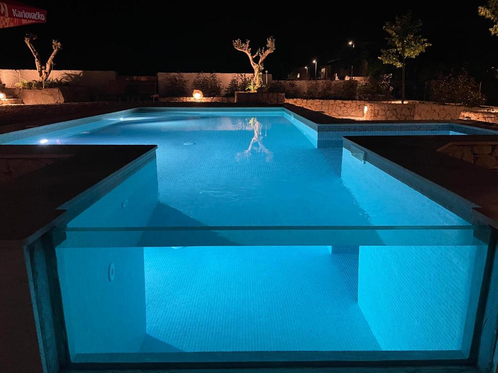 una piscina por la noche con luces azules en Vacation House Lavanda NEW! Heated pool, en Zadvarje