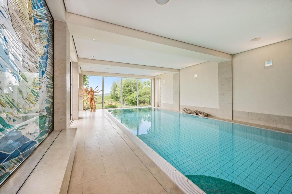 a swimming pool in a house with a wall of windows at Wellness-Apartment mit Wasserblick, Pool, Sauna & Fitnessbereich in Rankwitz