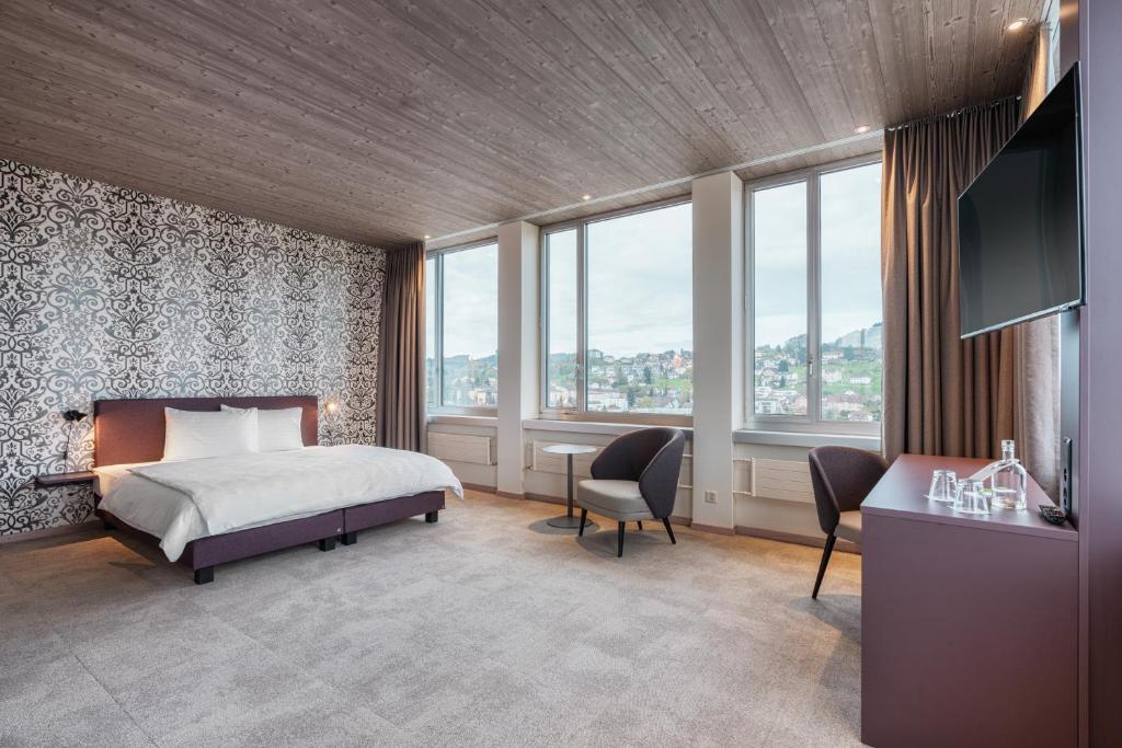 ein Schlafzimmer mit einem Bett und einem Schreibtisch sowie einige Fenster in der Unterkunft b-smart hotel Menziken in Menziken