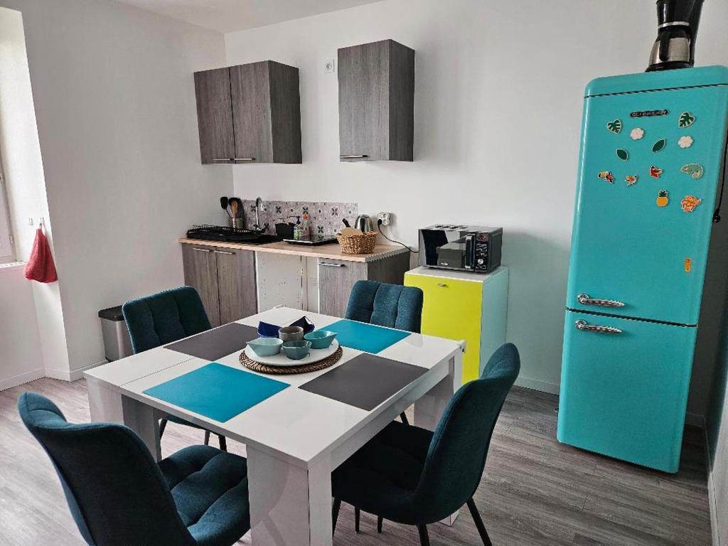 una cucina con tavolo, sedie e frigorifero blu di Appartement 4 personnes vue mer à Santec au pied de la plage du Dossen a Santec