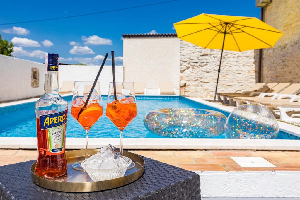 a table with two glasses and an umbrella and a pool at Villa Laura - Orihi in Barban