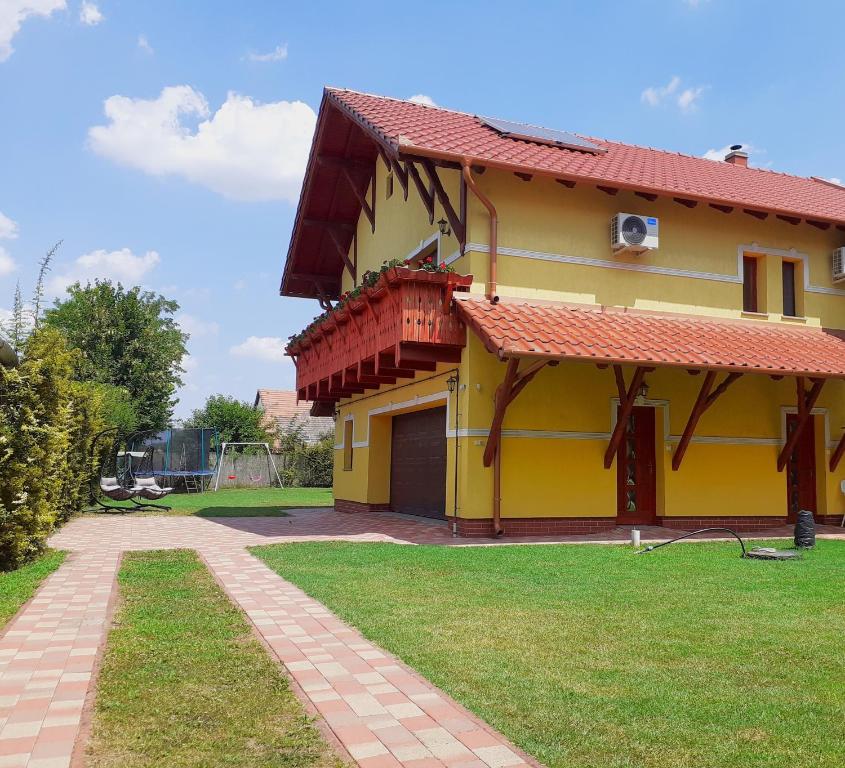 una casa amarilla con techo rojo en Klaudia Vendégház en Mórahalom