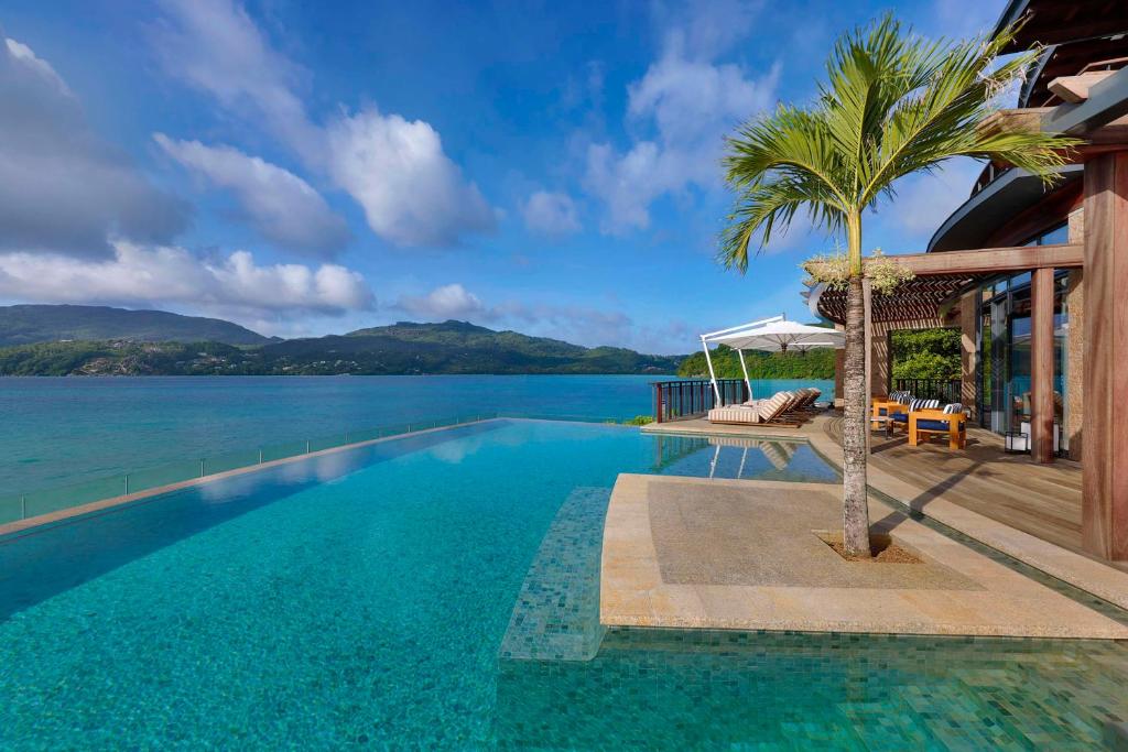 uma piscina com uma palmeira ao lado de uma casa em Mango House Seychelles, LXR Hotels & Resorts em Baie Lazare Mahé