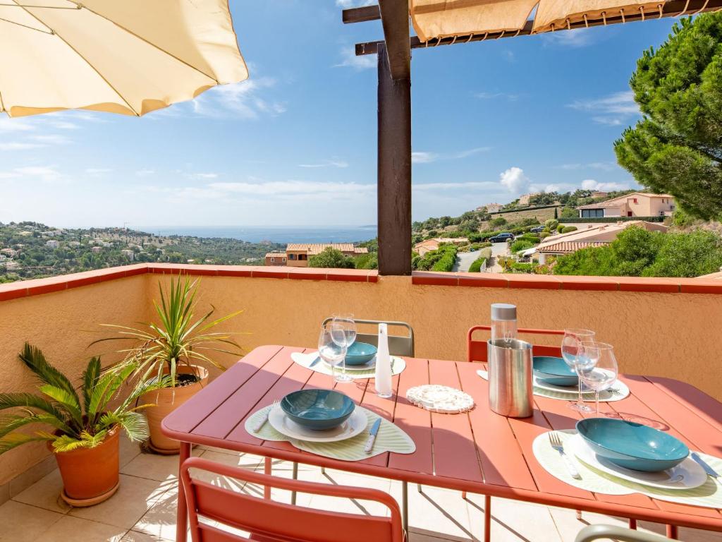 une table avec des assiettes et des verres sur un balcon dans l'établissement Apartment Les Hauts des Issambres-14 by Interhome, aux Issambres