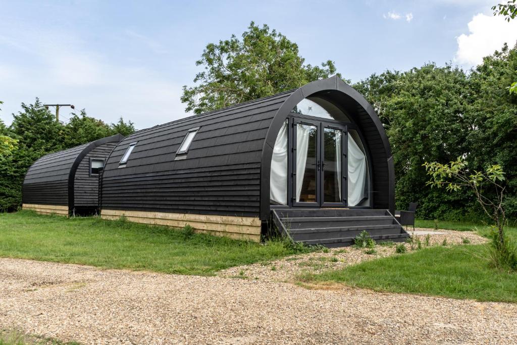 ein schwarzes Kuppelhaus mit einem Fenster im Gras in der Unterkunft Glamping Pod Two - Holly Tree Barns in Halesworth